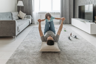 Vater spielt mit seinem Sohn in einem modern eingerichteten Wohnzimmer